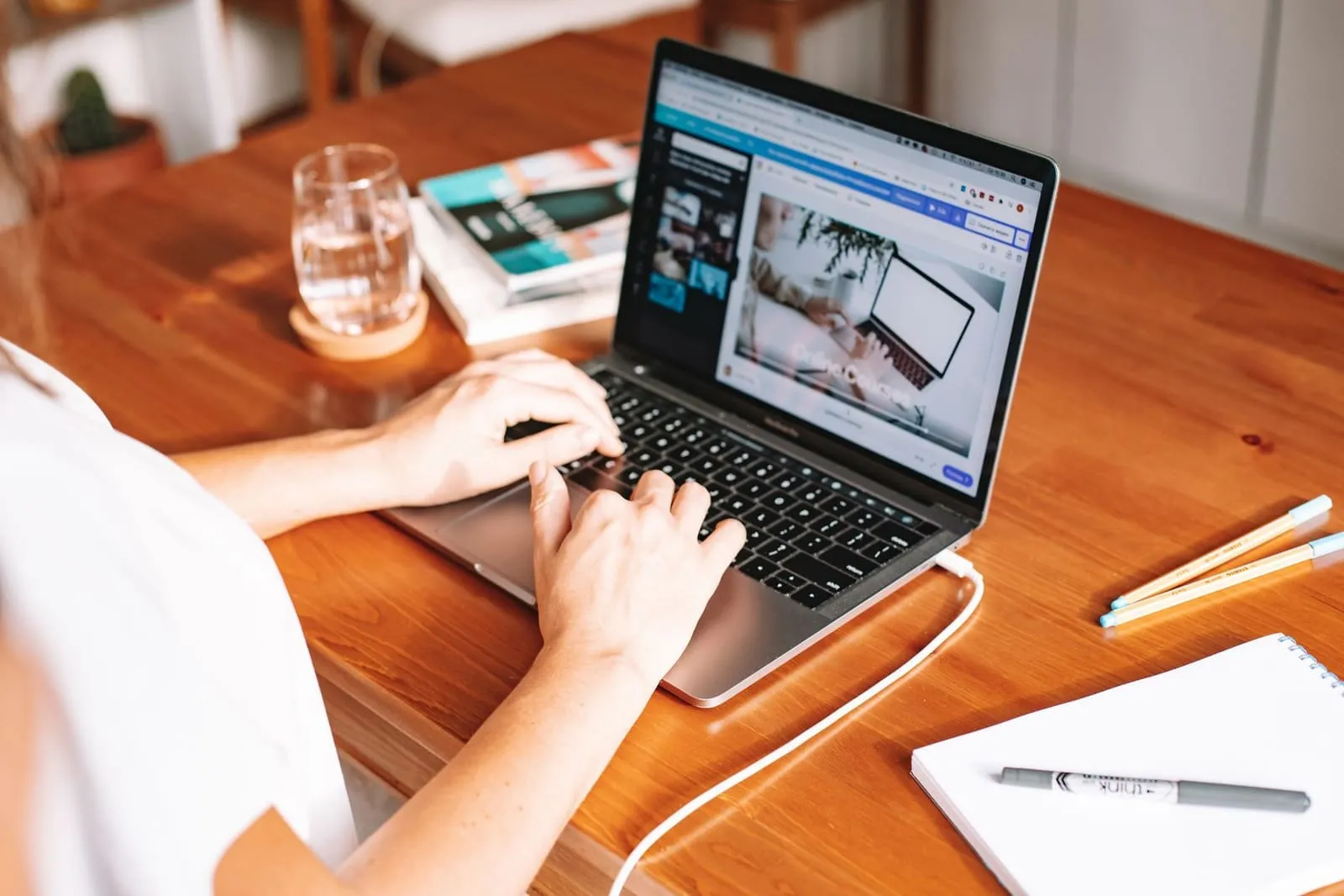 A person using a laptop at a wooden desk